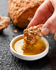 Woman dipping bread into bowl of tasty olive oil
