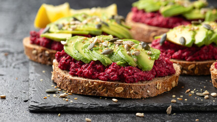 Avocado, beetroot hummus toast on dark sourdough bread topped with pumpkin, sunflower, hemp and flaxseed. Vegan, vegetarian super food