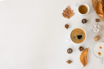 Autumn composition with cups of coffee and leaves on a white background.