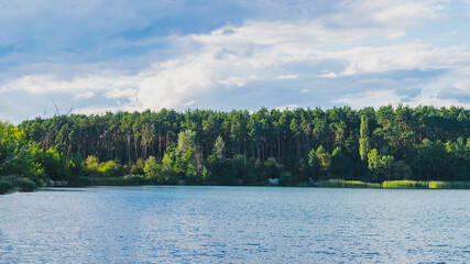 Fototapeta premium Panorama of Zhytomyr, a forest with a river against the backdrop of residential buildings in the distance.