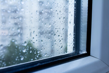 Drops on a double-glazed window, modern glass in the windows, rain outside the window, selective focus