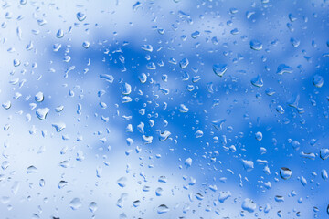 Water drops on glass against blue sky close-up