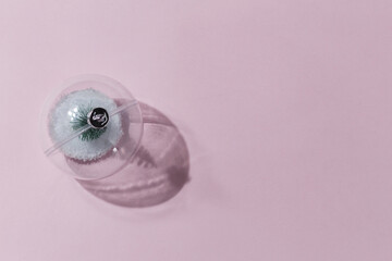 Minimalistic composition of a Christmas toy on a pink background. The concept of celebrating christmas and new year.