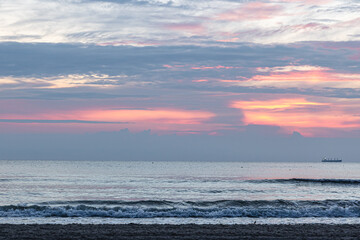 Fototapeta premium Texture sea waves at sunset with pink clouds.
