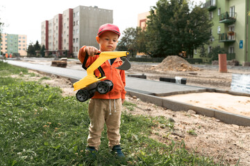 Child with excavator near construction site, dreams to be an engineer. Little builder. Education,...