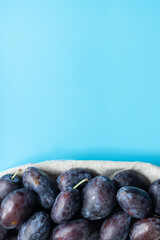 Pflaumen in einem Korb auf einem blauen Untergrund