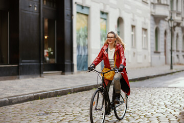 happy elegant female outside in city riding bicycle
