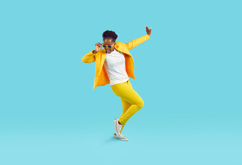 Cheerful funny woman in good mood dancing cheerfully isolated on light blue background. Young...