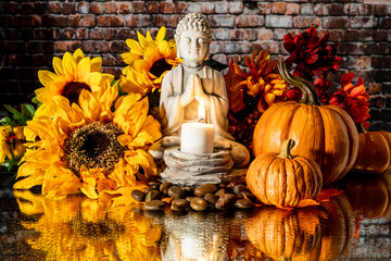 horizontal fall Buddha on wet mirror with burning candle   pumpkins and sunflowers