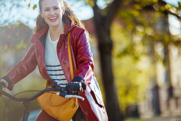 Fototapeta na wymiar happy elegant woman outdoors on city street riding bicycle