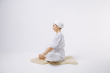 A girl in white clothes does yoga in a white room