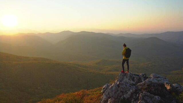 A man standing and praying on the edge of a rock searching for wisdom in the beautiful mountains during a fantastic sunset