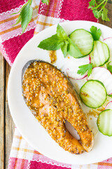 Salmon steak baked in honey and mustard marinade. Salmon on a white plate with fresh vegetables....