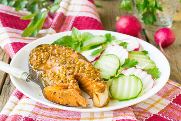 Salmon steak baked in honey and mustard marinade. Salmon on a white plate with fresh vegetables. Wooden background