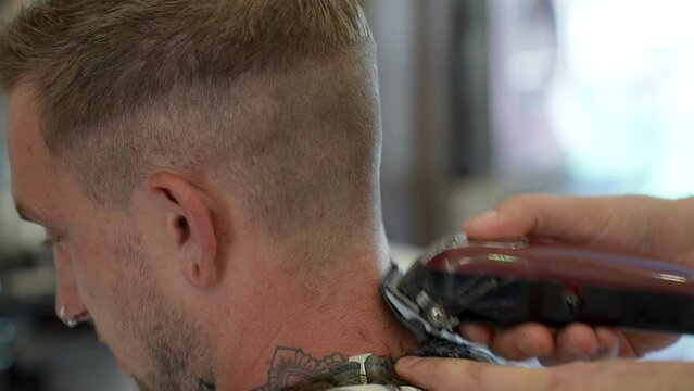 Barber Doing A Close Buzz Cut To Young Mans Neck And Hair Line