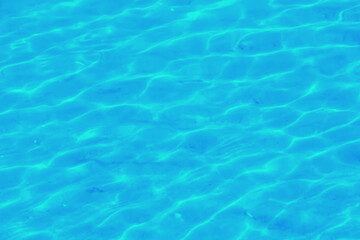 Fototapeta na wymiar Water ripple texture background. Wavy water surface. Blue sky reflected in the water.