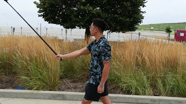 Man Walks With Selfie Stick In Park