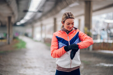 Young woman using smartwatch while running outside on a cold winter day