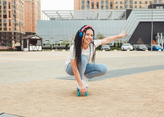 A beautiful young girl with dreadlocks rides a skateboard in sunny weather. generation z