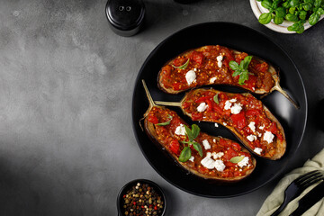 Grilled baked halves of eggplants stuffed with red sauce, chopped tomatoes, sweet pepper, feta...