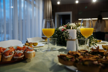 Glasses with yellow juice on the table, with flowers in the room