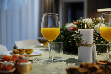 Glasses with yellow juice on the table, with flowers in the room