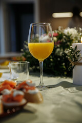 Glasses with yellow juice on the table, with flowers in the room