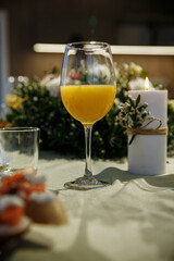 Glasses with yellow juice on the table, with flowers in the room