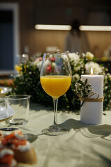 Glasses with yellow juice on the table, with flowers in the room