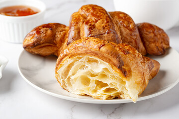 Fresh sweet croissants with apricot jam for breakfast. Continental breakfast on a white table