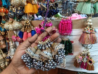 hand holding junk jewelery in indian local bazaar market,selective focus,blur background