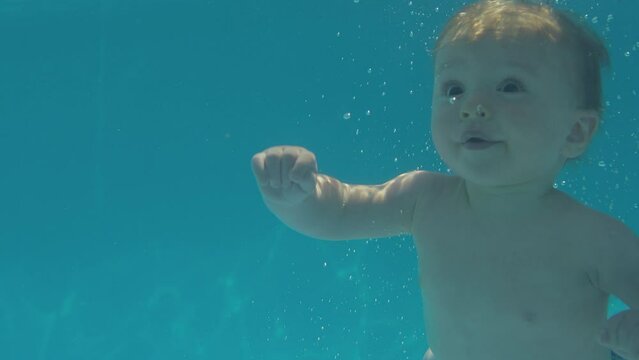 Baby boy with family on summer holiday swimming underwater in pool - shot in slow motion 