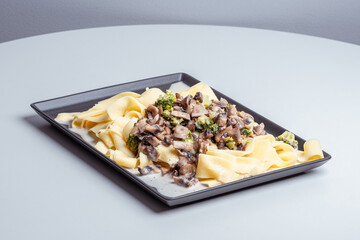 gray plate with delicious pasta with mushrooms, broccoli and parmesan cheese in a cream sauce. food background.