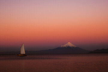 Fototapeta premium barco de vela en paisaje rosado al atardecer