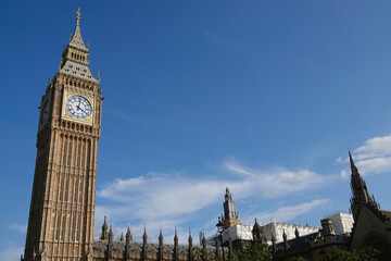 Obraz premium Elizabeth Tower, known as Big Ben, rising into a blue sky above the Houses of Parliament in Westminster, London, UK. 