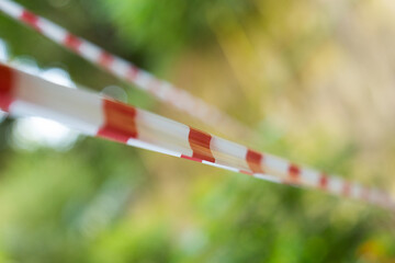 White-red protective tape. Barrier tape on a green background. White and red strip barrier tape.