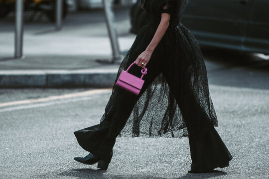 Street style, woman wearing puffy sleeves midi dress, high waist black flared pants, pink leather crocodile print pattern handbag and black shiny leather heels shoes.