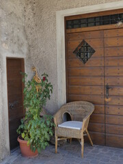 Fototapeta na wymiar Pflanze und Sessel neben einer massiven Eingangstür aus Holz