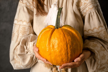 A girl in a Ukrainian dress holds a pumpkin, a symbol of rejection of a suitor