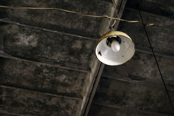 Old metal round lamp under a concrete ceiling in an abandoned room