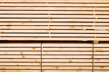 Background from wooden boards close-up. Stacked stacks of wooden planks. Lumber warehouse, wood drying, building material.	