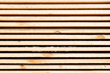 Background from wooden boards close-up. Stacked stacks of wooden planks. Lumber warehouse, wood drying, building material.	