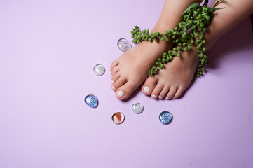 Naklejka na ściany i meble legs with manicure on a purple background with pebbles. advertising salon manicure nail art hand cream