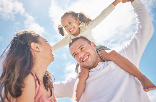 Children, Family And Love With A Girl On The Shoulders Of Her Dad Outside With Her Mother Watching On Against A Blue Sky. Kids, Happy And Smile With A Daughter Having Fun With Her Parents Outdoor