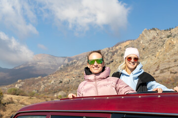Scenic view two young adult woman friends enjoy having fun sit on car roof at adventure suv offroad...