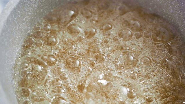 Close up view. Caramelizing sugar in saucepan to make homemade lollipops.