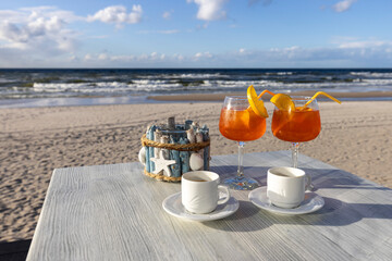 Beach cafe, two cups of coffee and drinks on the table. In the background the Baltic Sea and an empty beach, Island Wolin, Miedzyzdroje, Poland