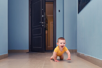 Toddler baby crawls out of the open apartment door. Child boy runs away from home. Kid age one year
