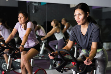 Portrait of woman doing cardio workout cycling bikes at fitness center