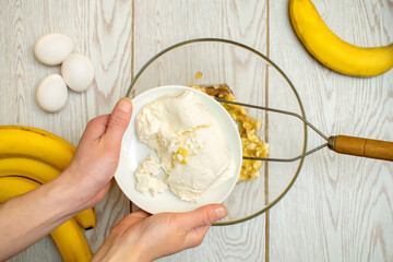 Woman hands mashing up several bananas, cottage cheese to bake into bread,cupcakes. chef preparing ingredients for making muffins,casserole at home kitchen cuisine, online cooking, recipe instruction